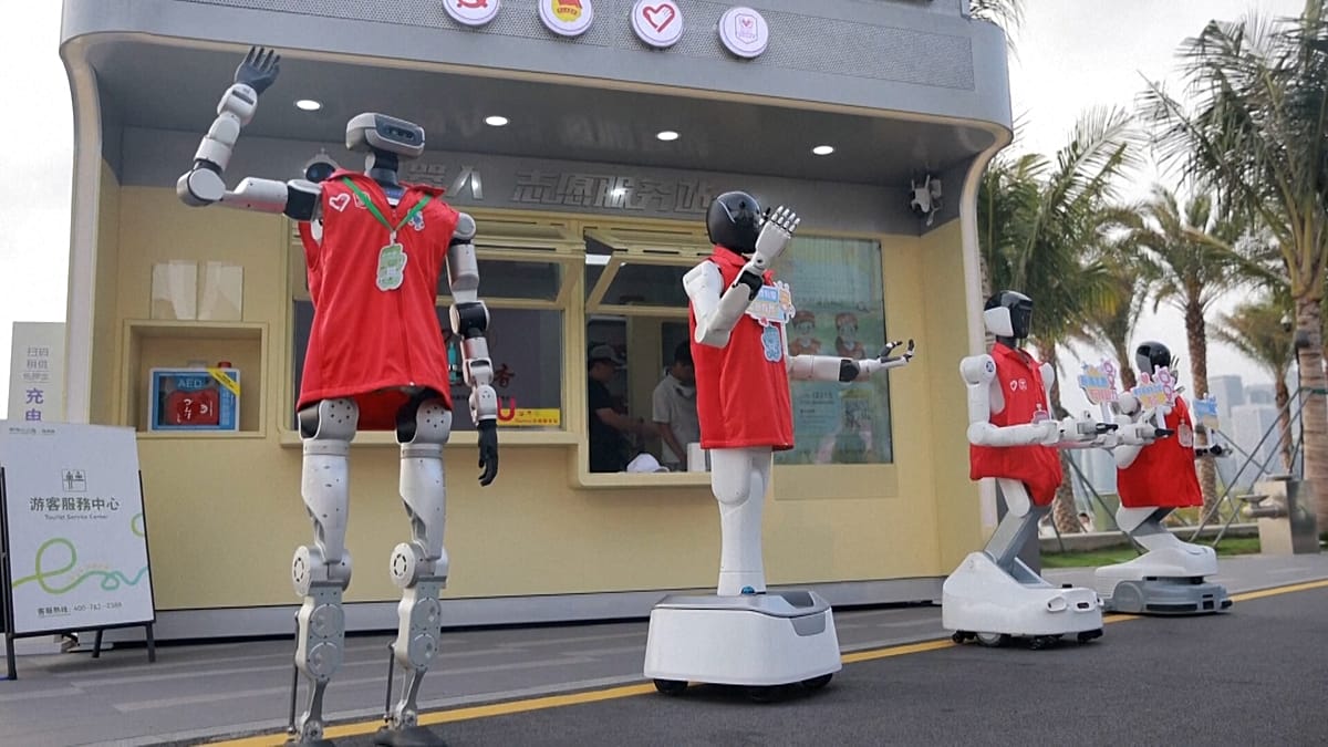 Humanoid robot volunteers stationed at service desk in Shenzhen public park interacting with visitors