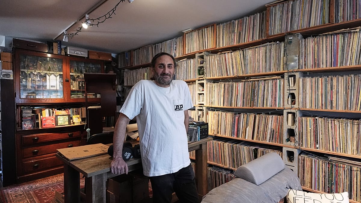 Aadam Jacobs standing in front of bookcase filled with LP records at his Chicago home