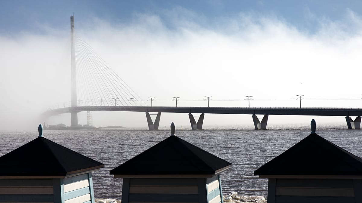Long pedestrian bridge stretching across water in Helsinki with walkers and cyclists enjoying car-free pathway