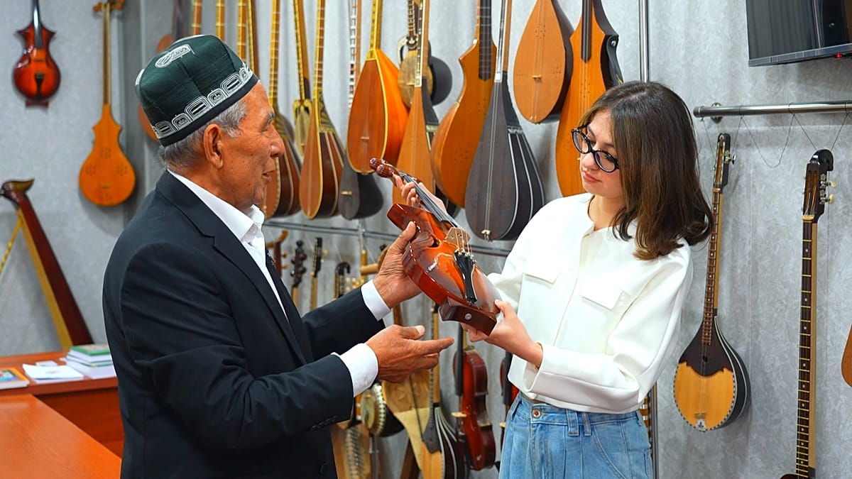 Master craftsman carefully shaping traditional Central Asian stringed instrument in workshop
