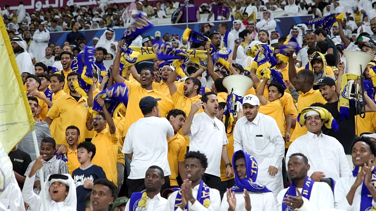 Packed crowd of fans waving flags at nighttime football match in Khalifa International Stadium, Doha