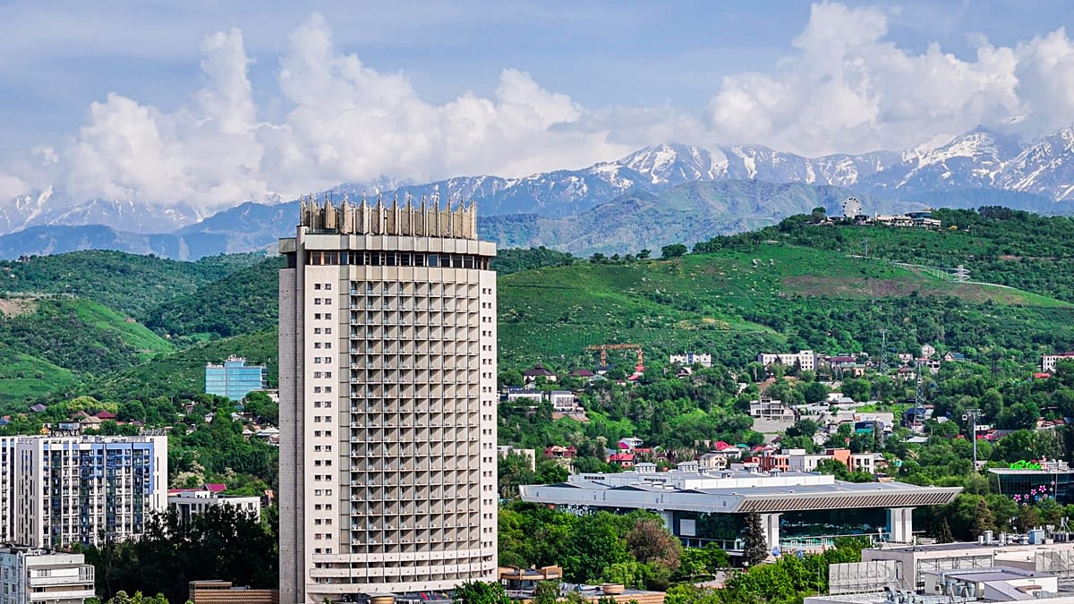 Panoramic view of Almaty cityscape with snow-capped Zailiysky Alatau mountains rising dramatically in background