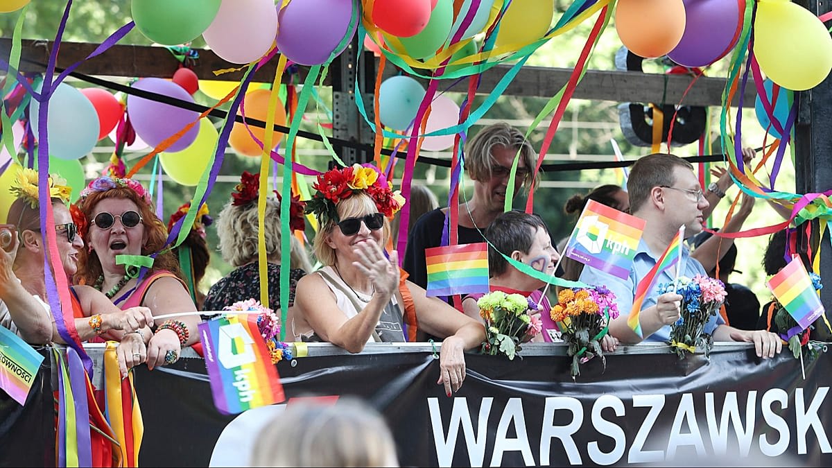 Two people hold hands celebrating outside Warsaw city hall after marriage registration