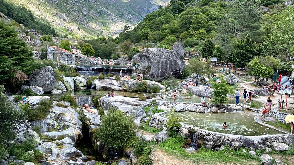 Crystal clear river beach surrounded by lush green forest in Portugal's mountainous interior region