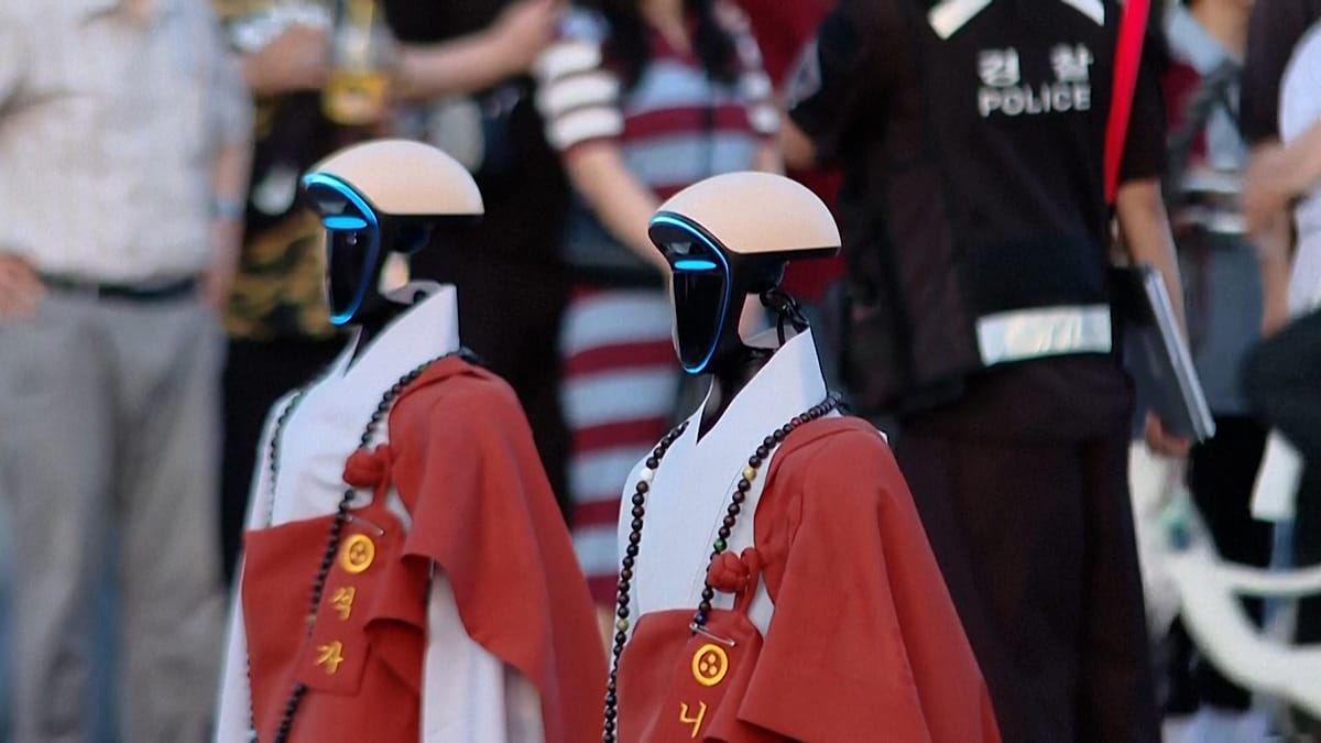 Four humanoid robots in traditional Buddhist robes walking in Seoul lantern parade with illuminated lotus decorations