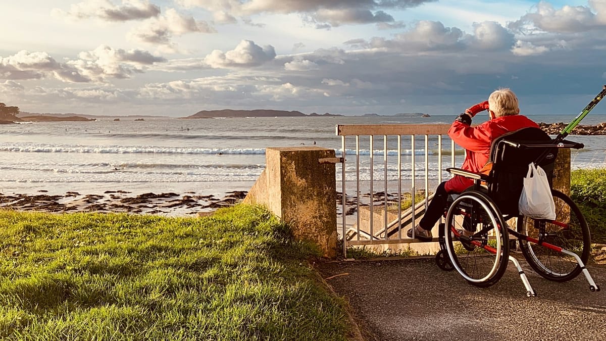 ** Wheelchair user exploring scenic European cobblestone street with accessible ramps and welcoming architecture