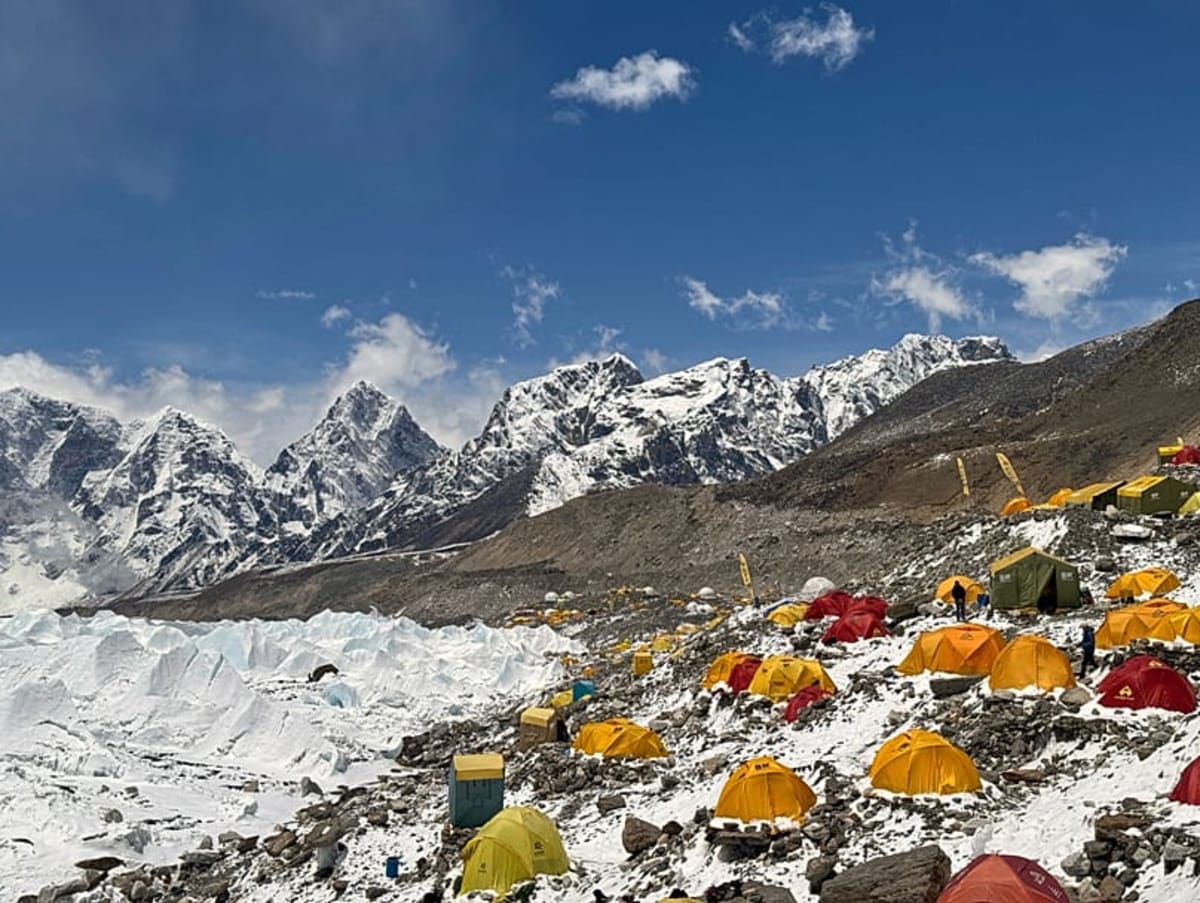 Mountain climbers ascending snowy slopes near Mount Everest summit with prayer flags