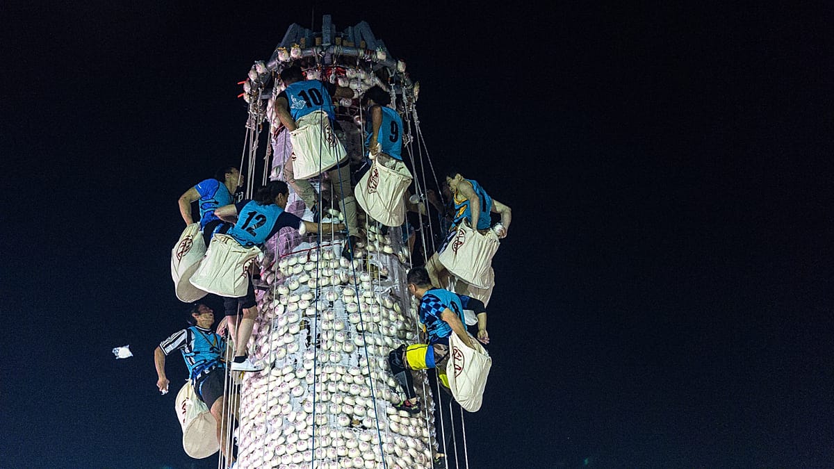 Climbers racing up tall tower covered in white buns during Hong Kong festival