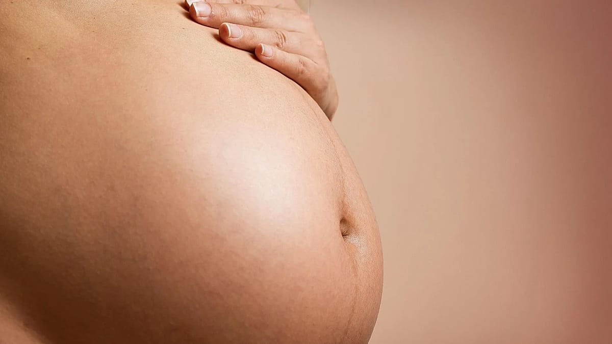 Pregnant woman wearing small ultrasound monitoring patch on abdomen in medical research setting