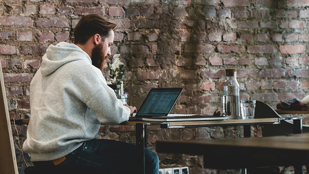 Digital nomad working on laptop in modern coworking space with city skyline view
