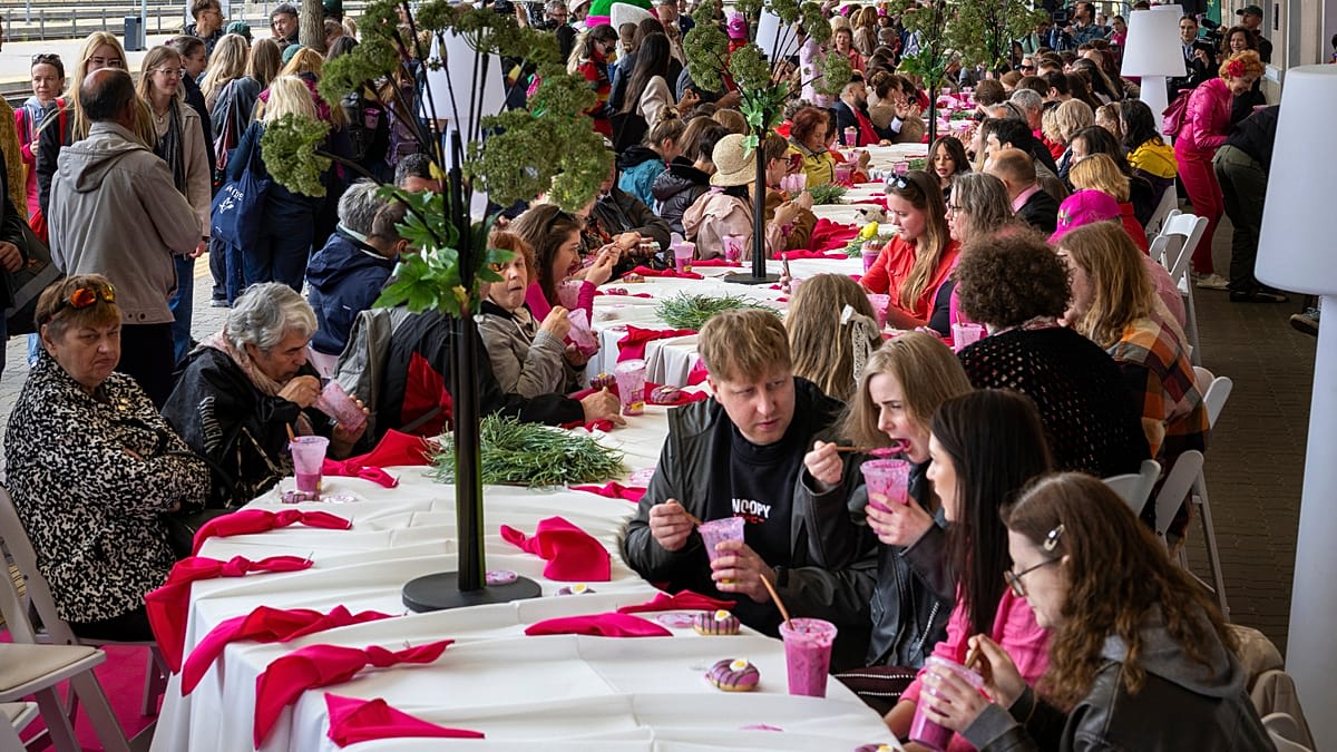 ** Crowds gather at long outdoor tables filled with bowls of bright pink beet soup during Vilnius festival