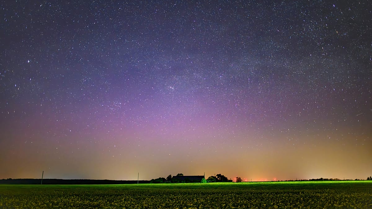 Vibrant green and purple northern lights dancing across dark night sky over German landscape