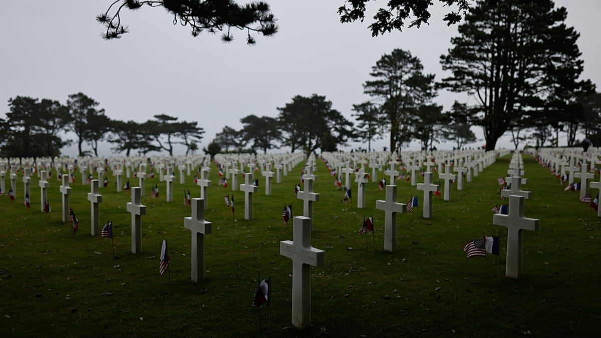 Six elderly World War II veterans attending D-Day memorial ceremony at Normandy beach monument
