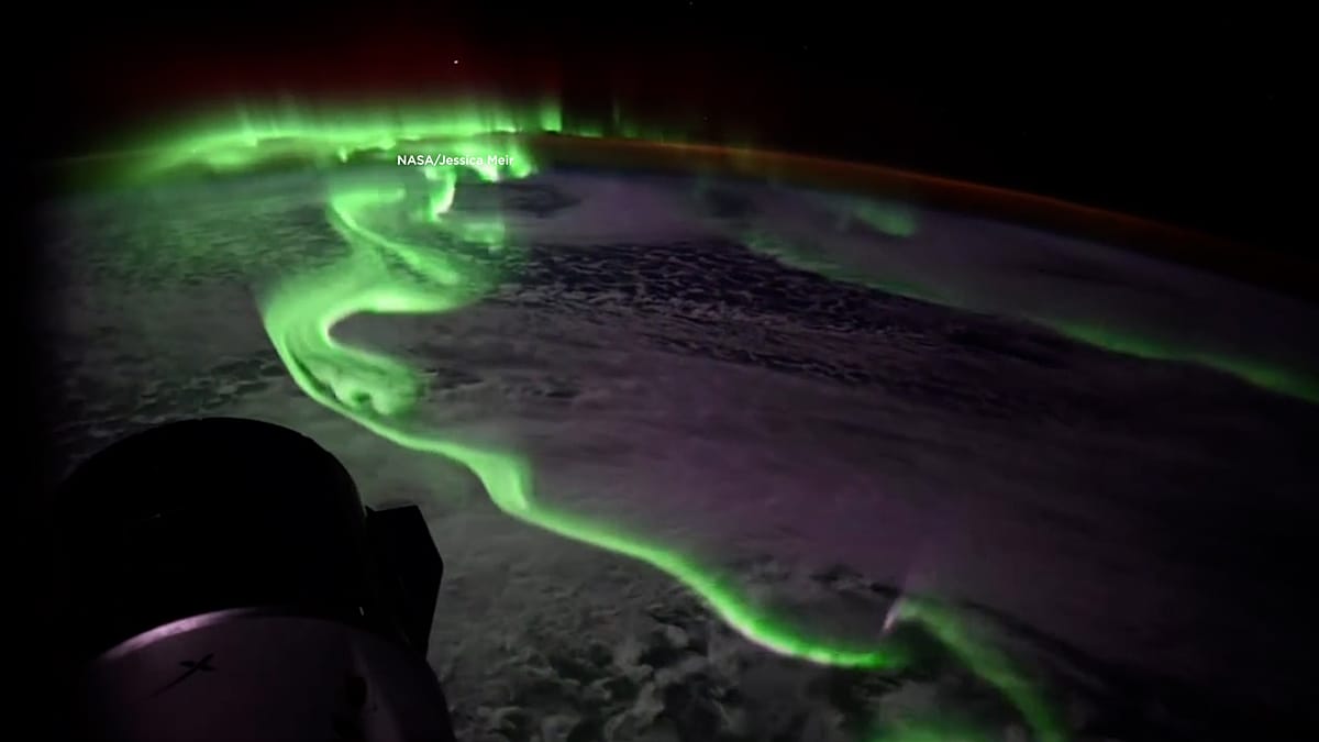** Brilliant green and purple Southern Lights dancing above Antarctica seen from space orbit