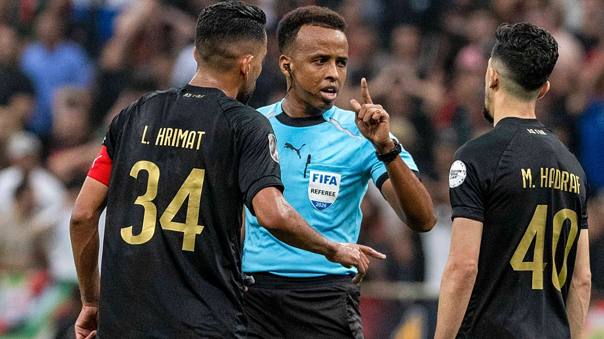 Somali referee Omar Artan in official uniform holding flag during football match