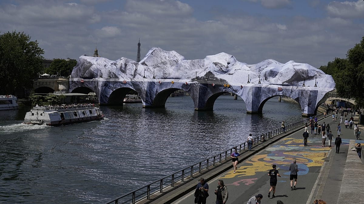 Visitors walking through JR's artificial cave installation covering the Pont Neuf bridge in Paris