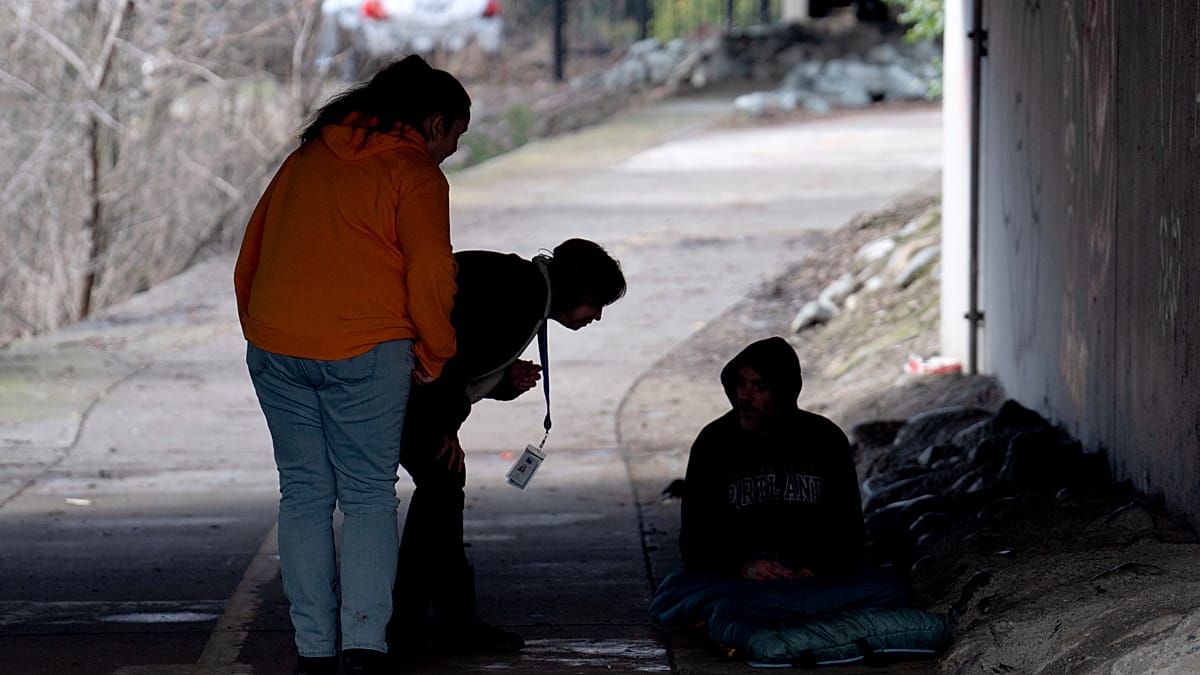 Healthcare workers providing compassionate street outreach to person experiencing homelessness in urban setting