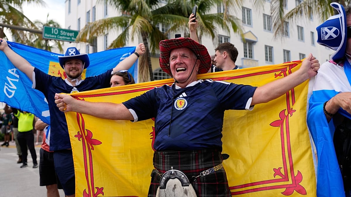 Enthusiastic international soccer fans celebrating together wearing colorful national team jerseys and flags