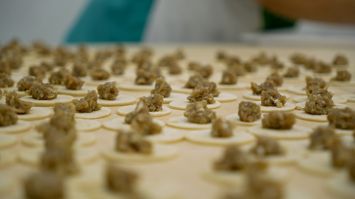 Traditional steamed dumplings arranged in bamboo basket showing delicate handmade pleating