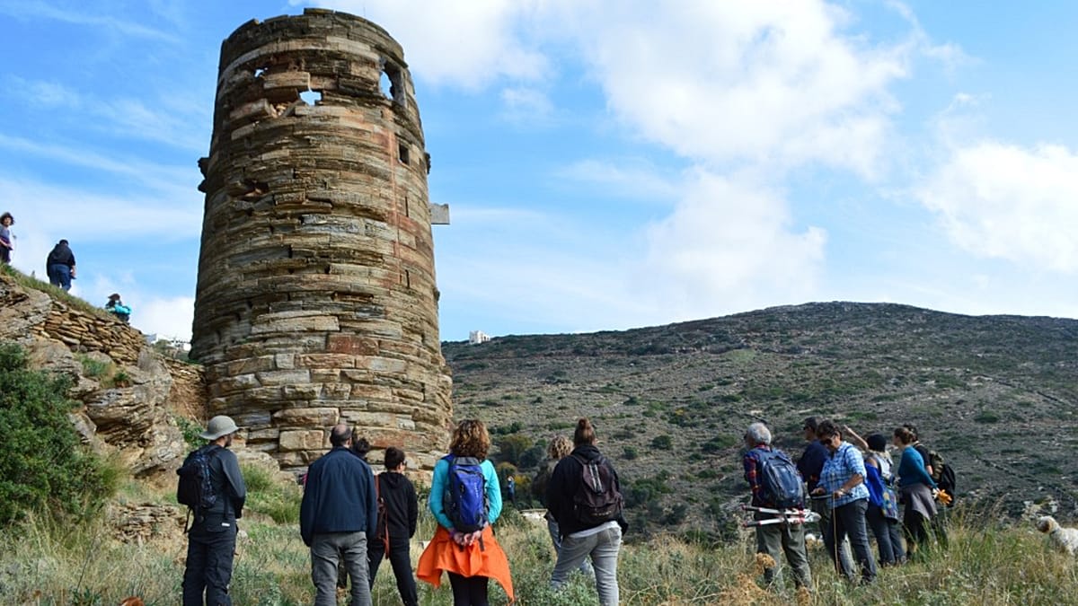 Hikers walking along scenic mountain trail on Andros island Greece surrounded by greenery