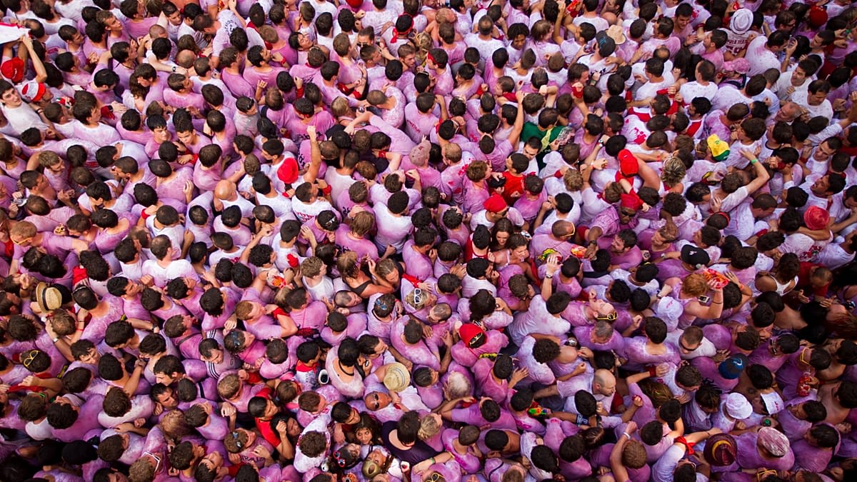 Crowded Town Hall Square in Pamplona with people in white clothing and red neckerchiefs celebrating San Fermín festival launch