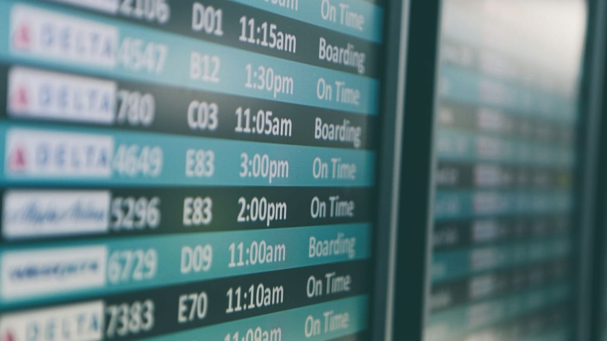 Traveler using smartphone flight app while walking through modern airport terminal
