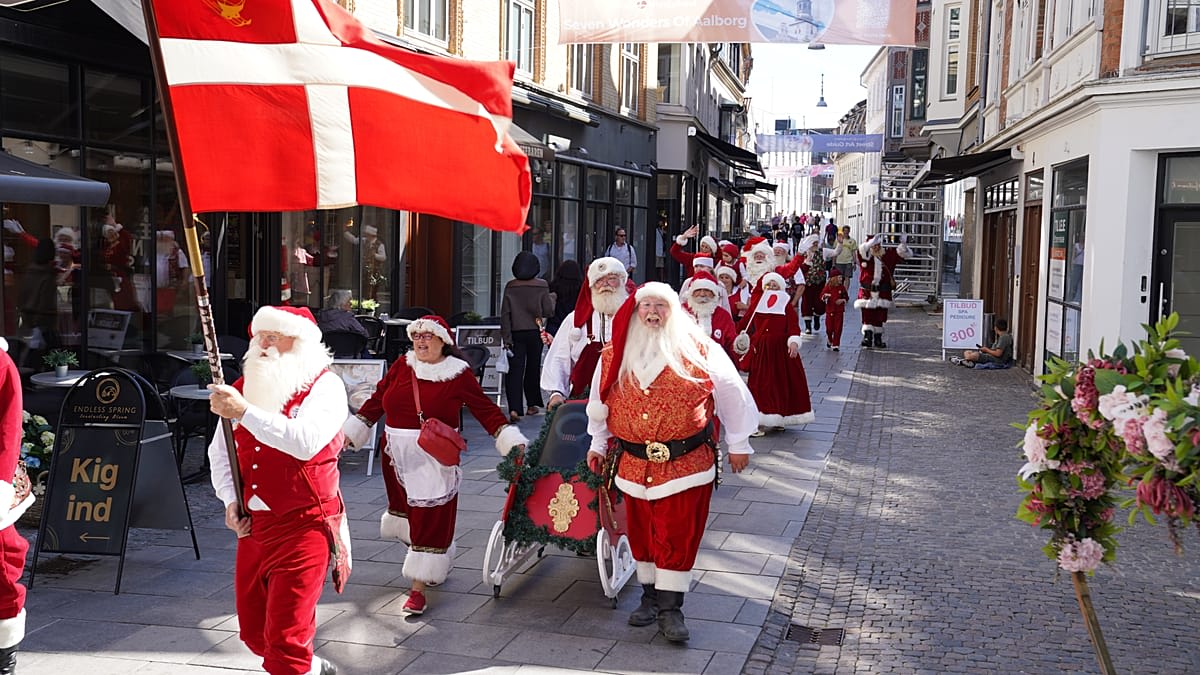 Professional Santas in red suits parade through sunny Aalborg Denmark streets in summer