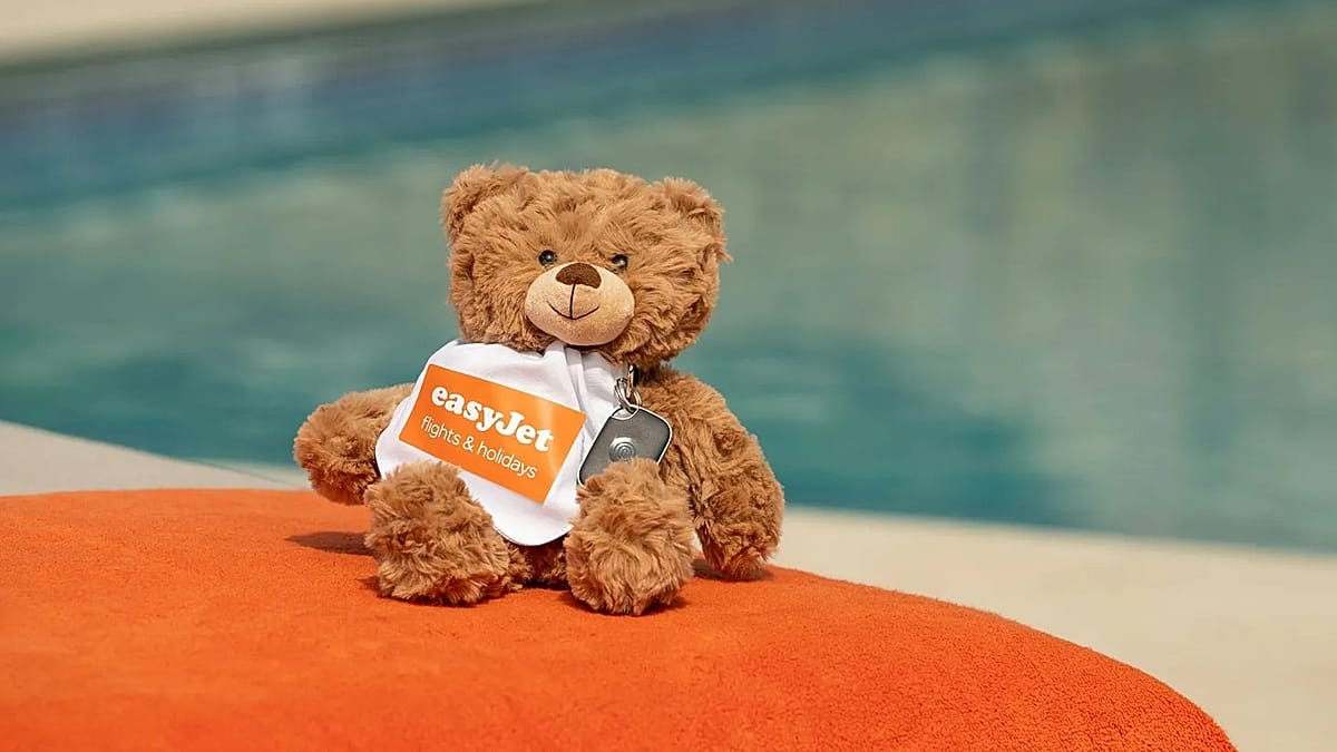 Child holding stuffed bunny with small tracking device attached at airport terminal