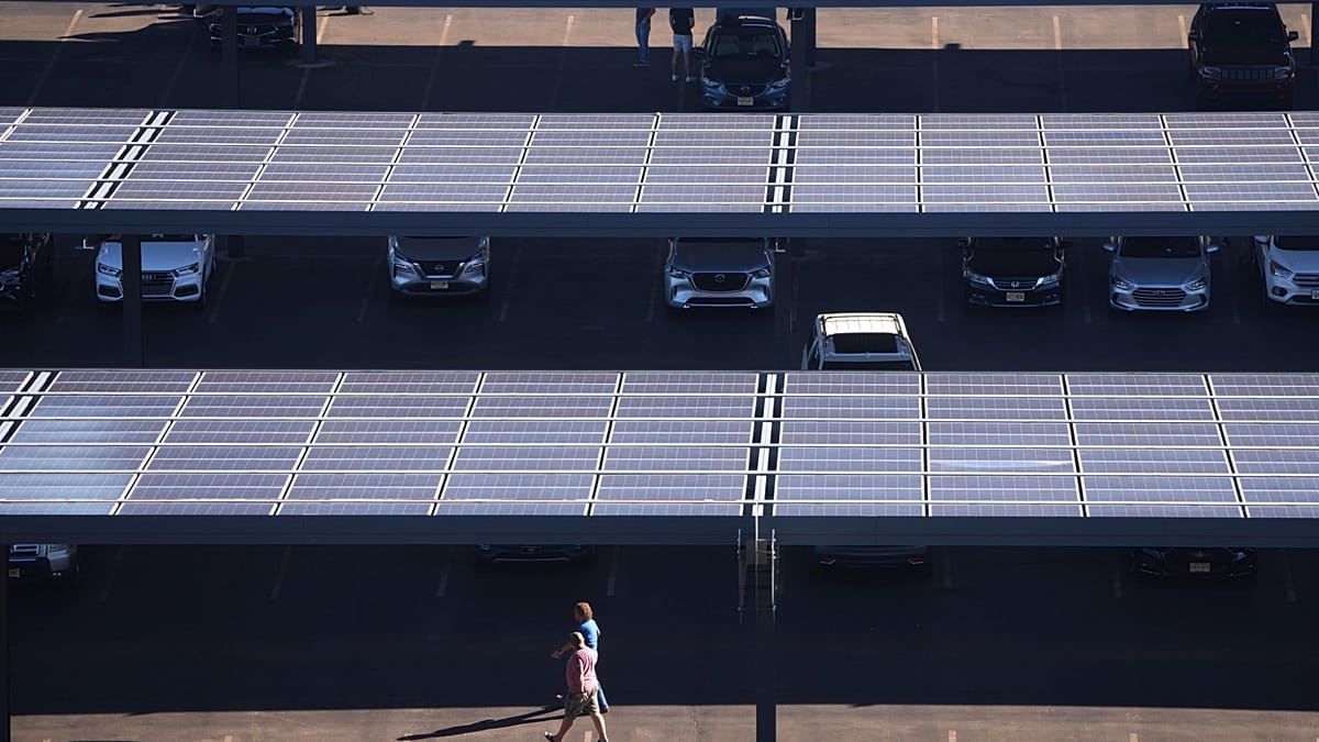 Rows of cars parked beneath blue solar panels providing shade and generating clean electricity