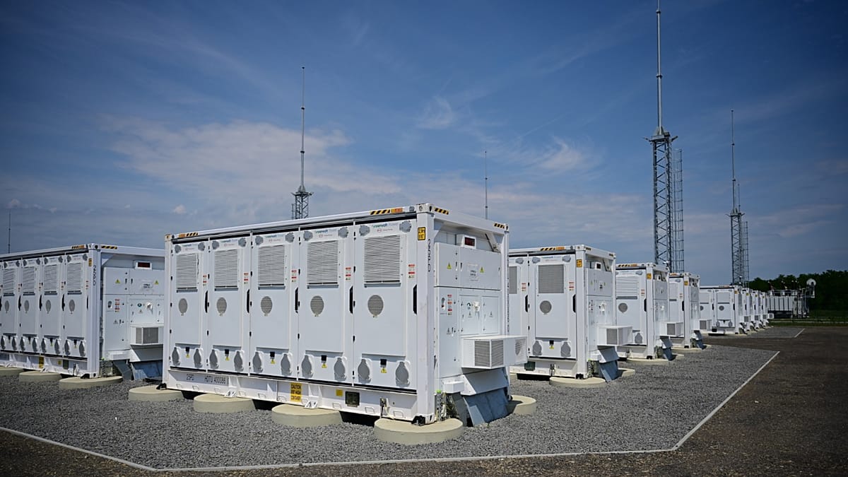 Large industrial battery storage facility with rows of white containers near renewable energy infrastructure