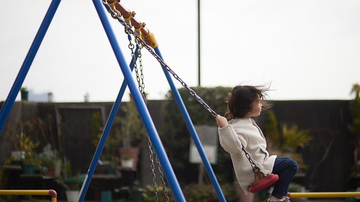 Happy elementary school child playing independently at recess while other children play nearby