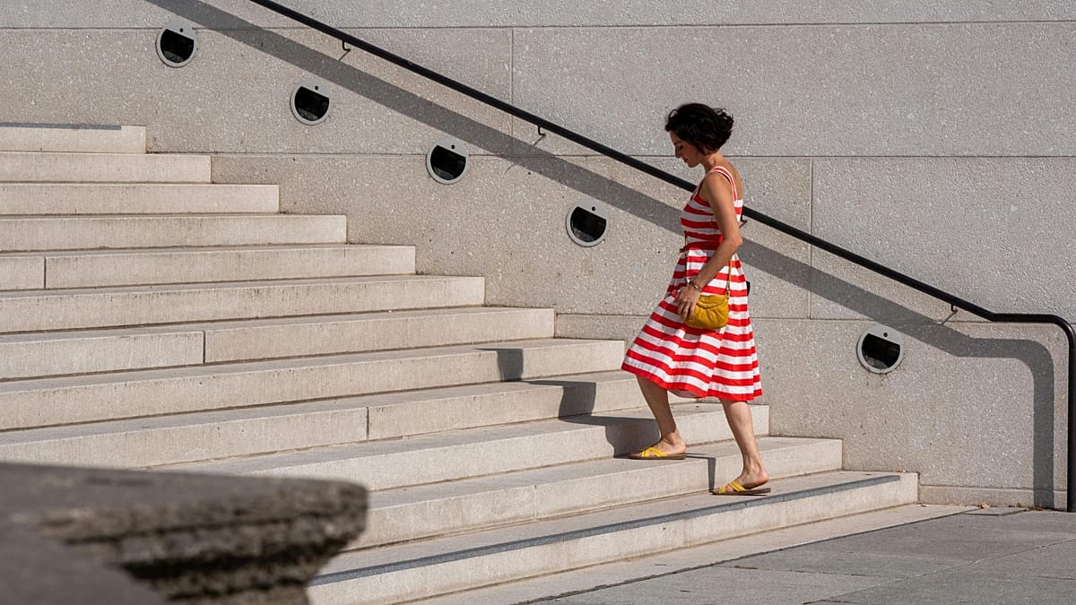 Person climbing modern office building staircase choosing stairs over elevator for heart health