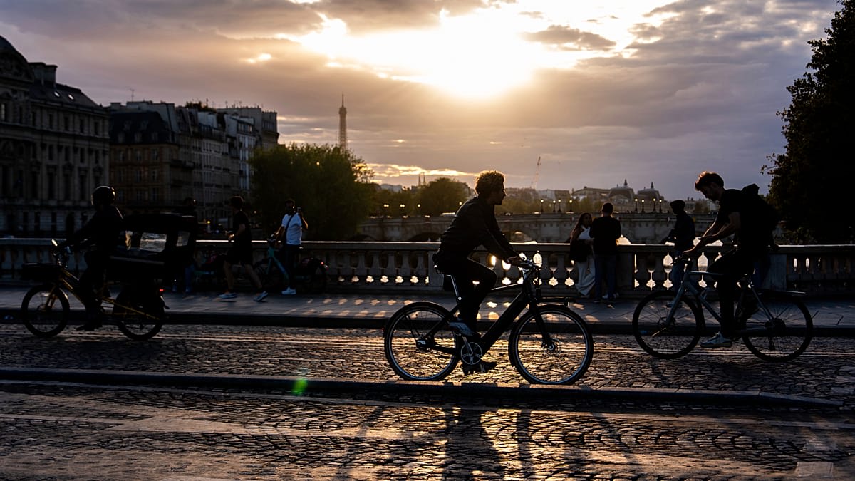 Tourists riding bicycles past the Eiffel Tower on a sunny day in Paris, France