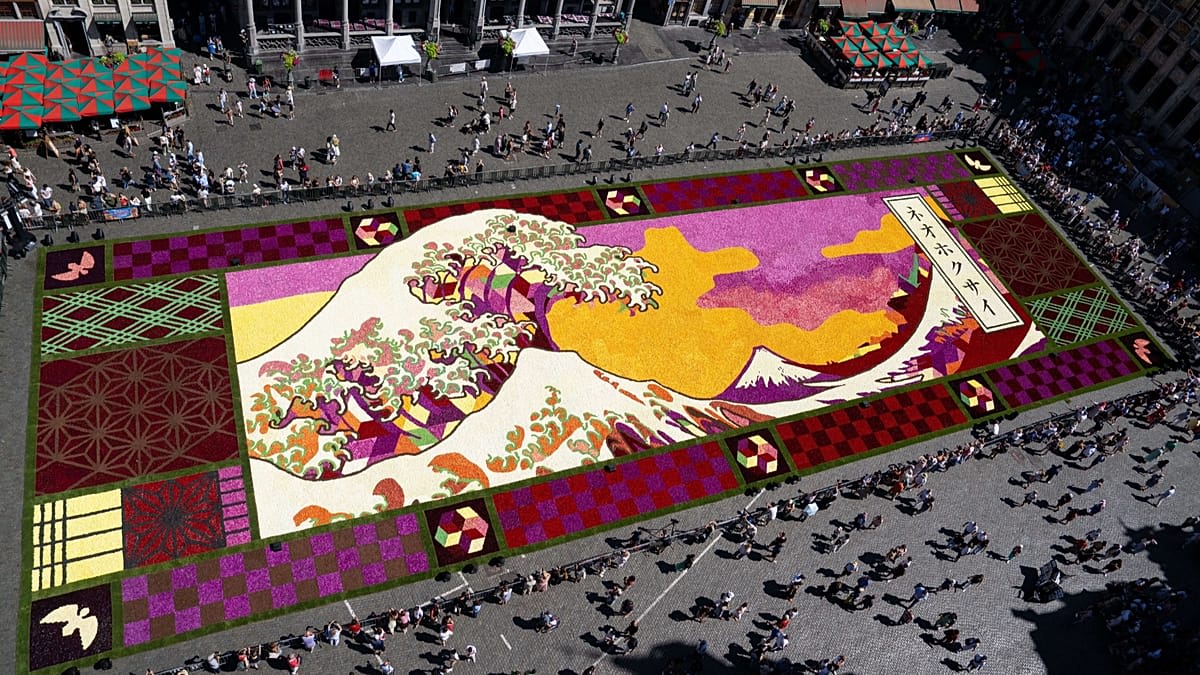 Aerial view of massive floral carpet depicting Japanese wave pattern on historic Brussels square