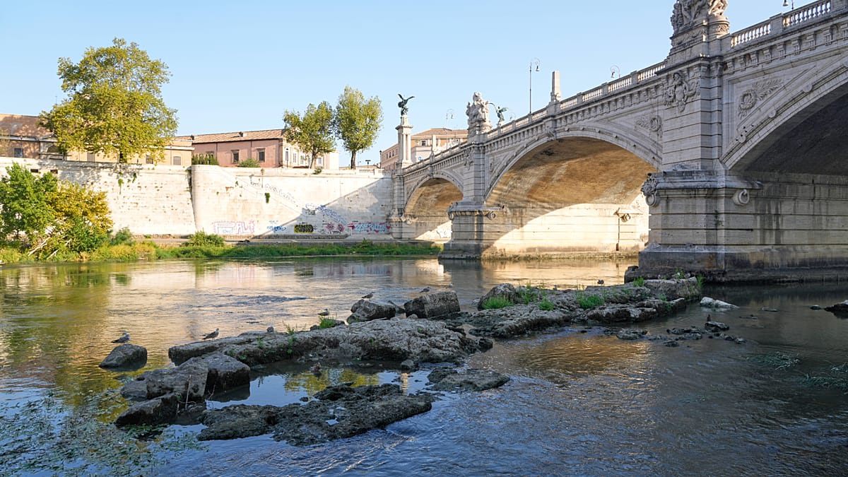Ancient stone pillars of Emperor Nero's bridge emerging from low waters of Rome's Tiber River