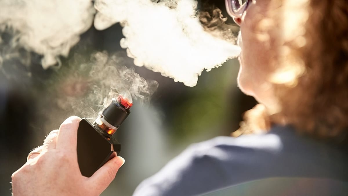Person breaking cigarette in half, choosing healthier alternative for quitting smoking successfully