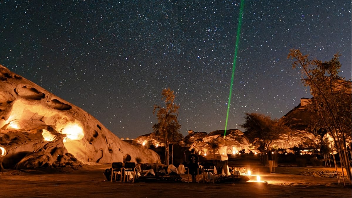 Luxury resort villa under starlit night sky with Milky Way visible over desert mountains