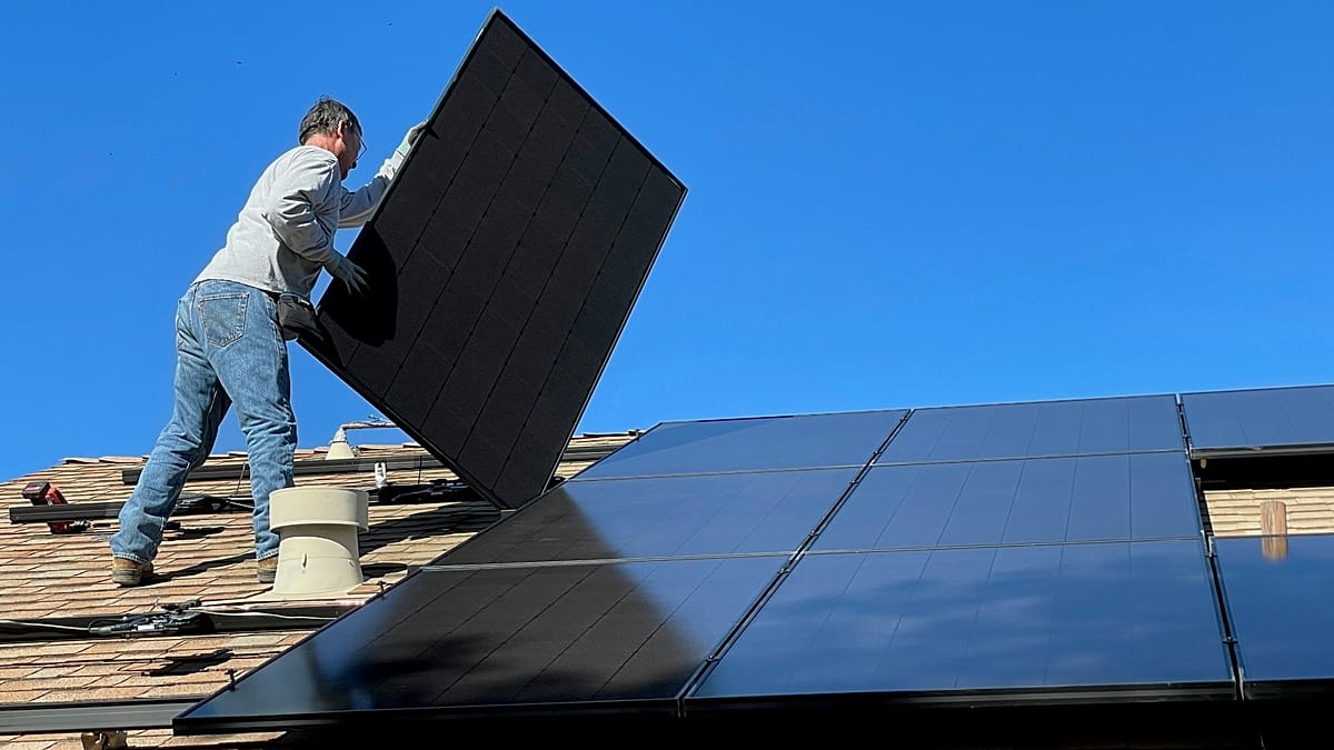 Modern solar panels installed on residential rooftop under bright blue sunny sky