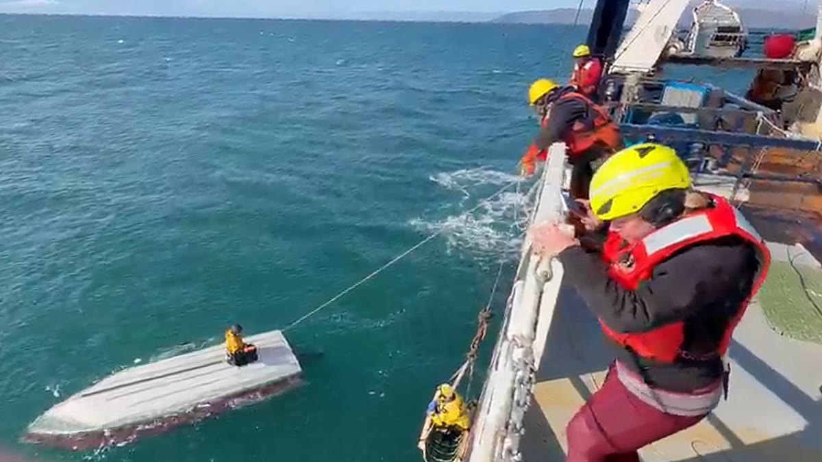 ** Coast Guard rescue crew helping teenage boy in yellow jacket aboard vessel in Alaska waters
