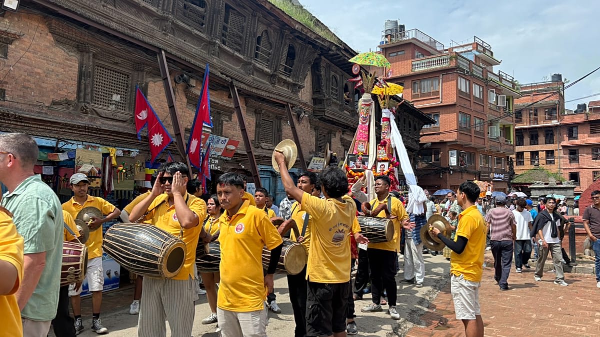 ** Colorful bamboo structures decorated with red and white cloth parade through crowded streets in Bhaktapur, Nepal