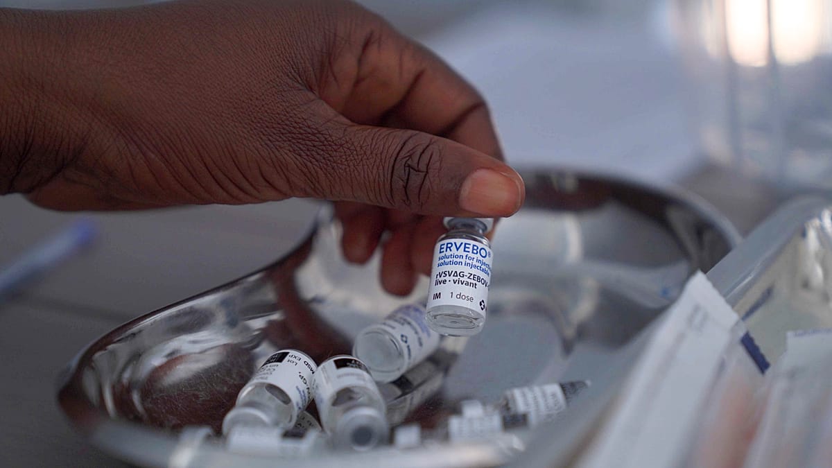 Healthcare workers in protective gear preparing Ebola vaccine doses for clinical trial administration in Congo