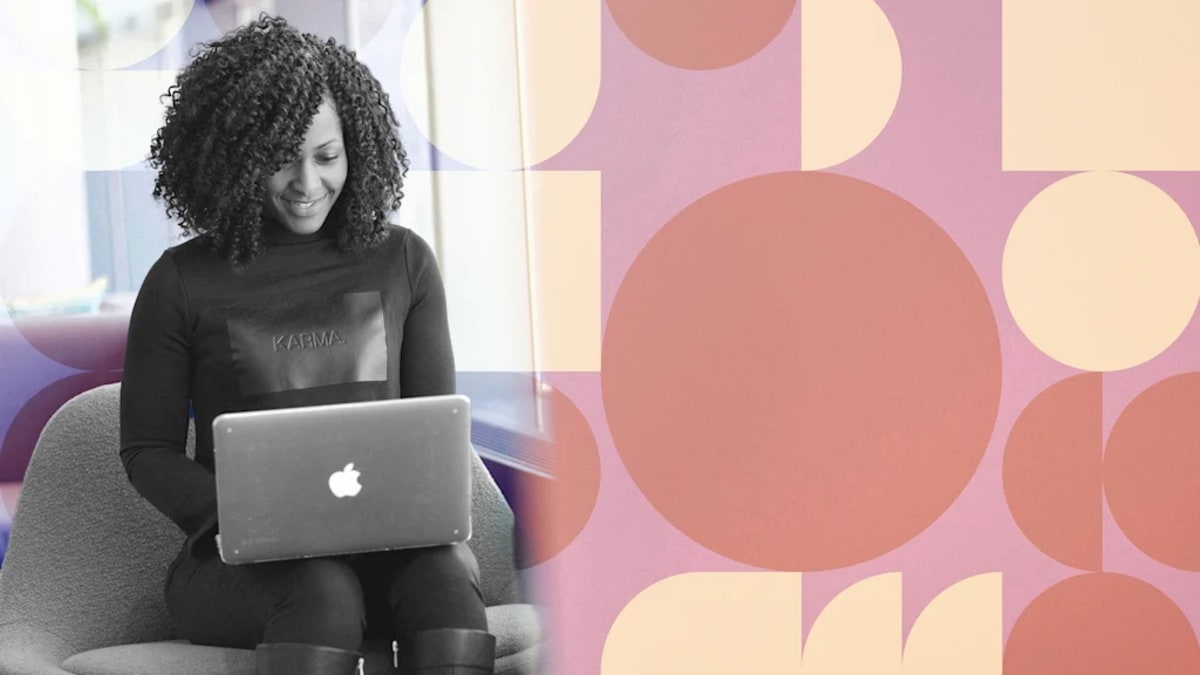 Black woman entrepreneur smiling confidently while working on laptop in modern office space