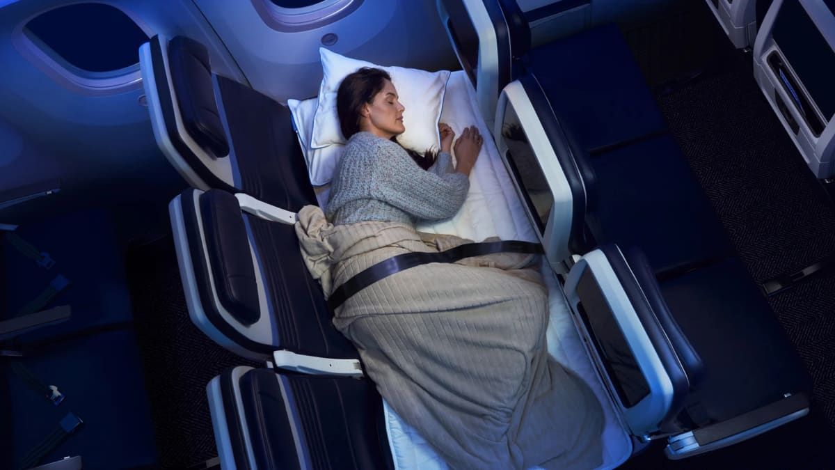 Three United Airlines economy seats converted into flat bed with blue mattress pad