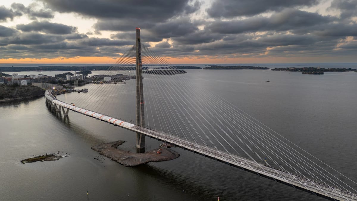 Wide pedestrian and cycling bridge curving gently across blue water in Helsinki, Finland