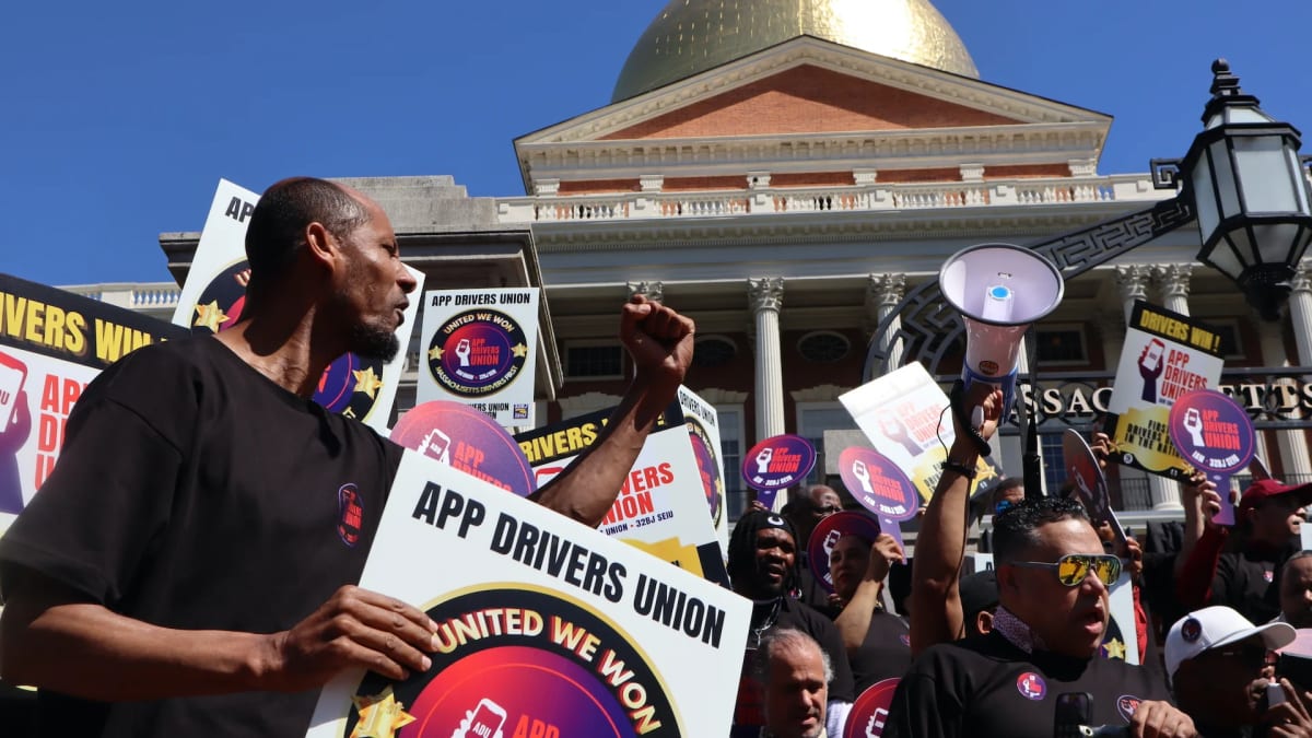 Uber and Lyft drivers celebrating with signs outside Massachusetts State House after historic union certification