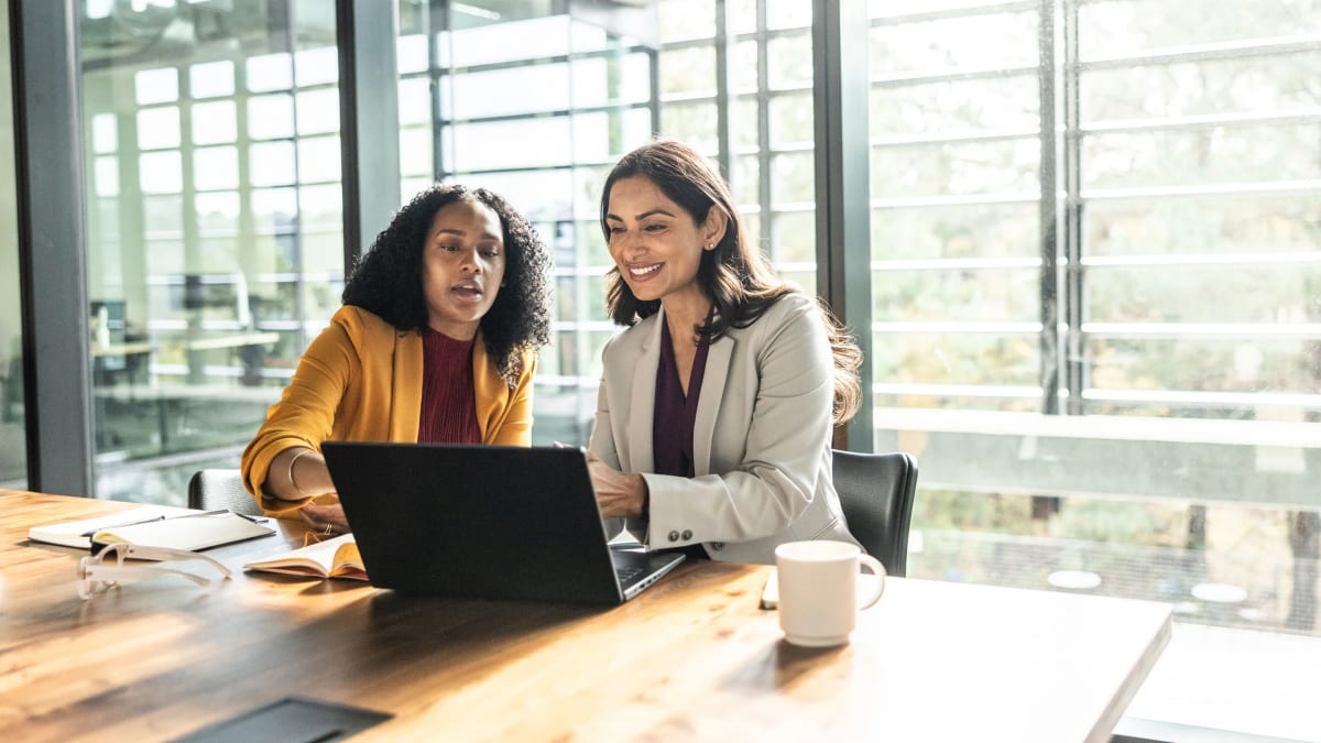 Professional woman working on laptop with AI interface graphics, symbolizing workplace technology transformation