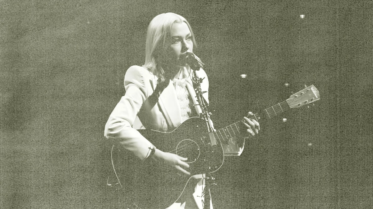 Phoebe Bridgers performing on stage at an intimate concert venue with engaged audience
