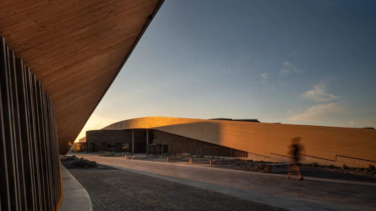 Modern library building with earth-toned walls emerging naturally from North Dakota Badlands landscape
