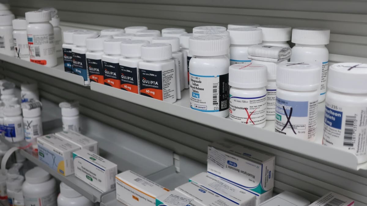 Senior citizen reviewing prescription medication bottles and healthcare bills at pharmacy counter