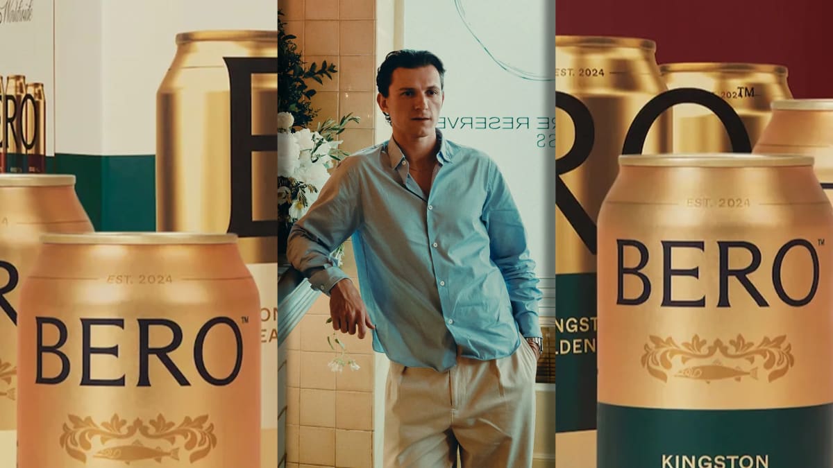Tom Holland smiling while holding a bottle of Bero nonalcoholic beer at promotional event